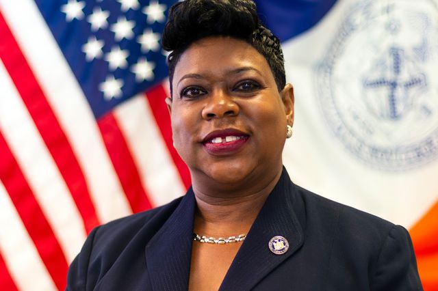 Photograph of Darcel Clark in front of the U.S. flag and NYC flag.